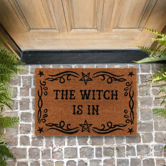 Enhance your home and create a welcoming space with this&nbsp;natural coir doormat printed with 'The Witch Is In' text and a flourished border. Makes a fun welcome at the front door of any witch's lair!
